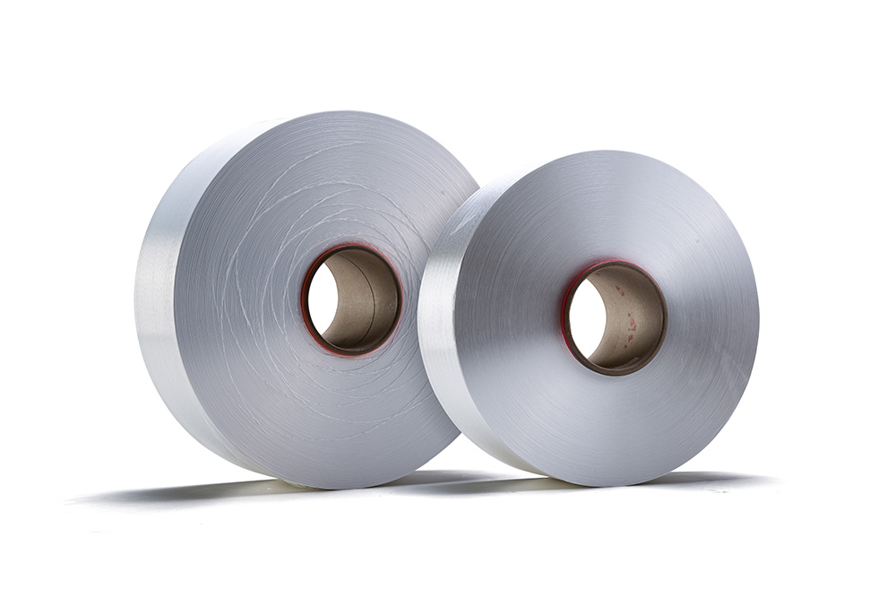 Two large rolls of white synthetic yarn or film standing on a white background, product photography, neutral mood