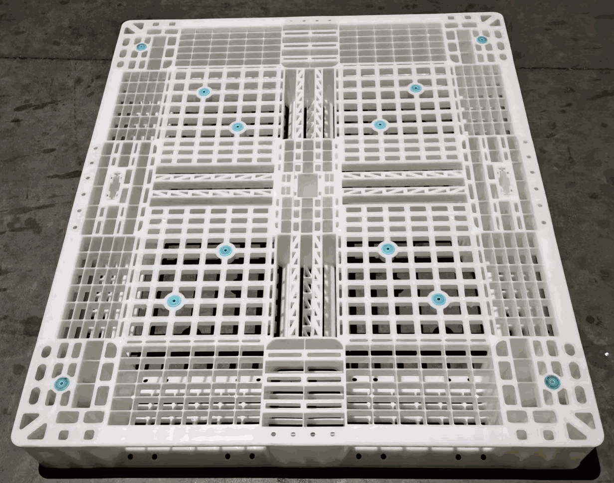 Close-up of a white plastic pallet with a grid pattern and blue accents resting on a concrete floor, industrial and neutral mood